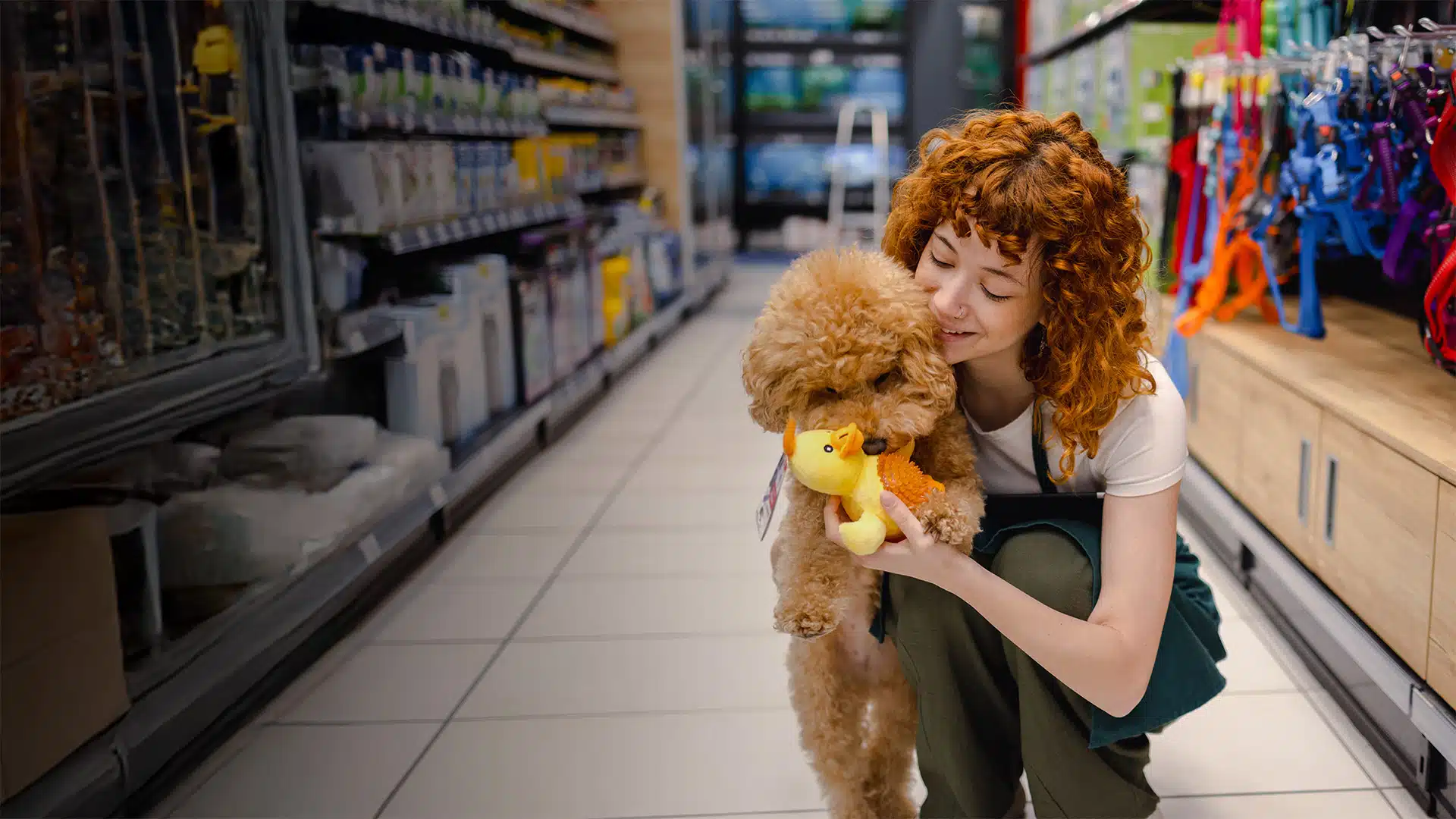 A woman in a pet store with her dog playing with a plush duck