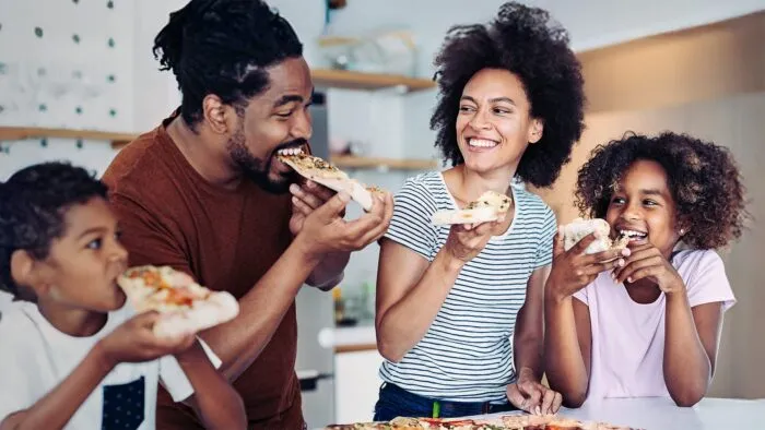 A family eating pizza around a kitchen island