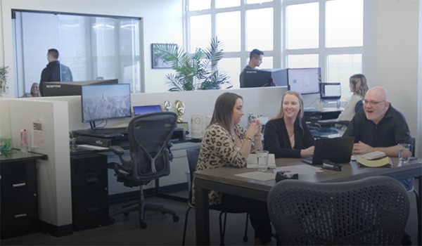Three people sitting around a table in a common area in an office.