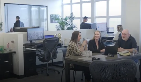 Three people sitting around a table in a common area in an office.