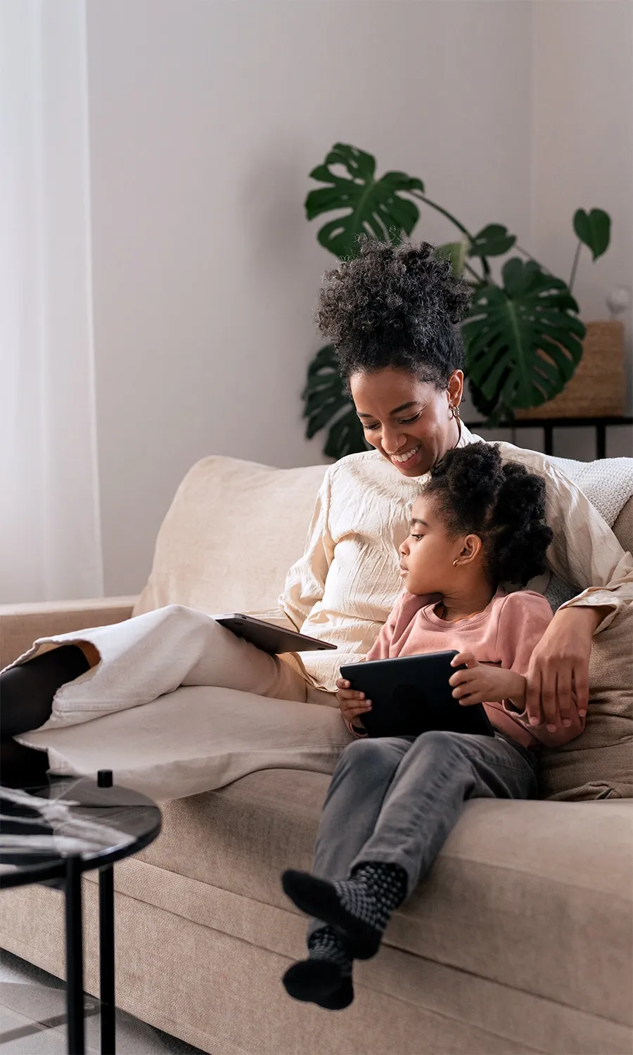 Woman and her child sitting on a couch watching tv on a tablet