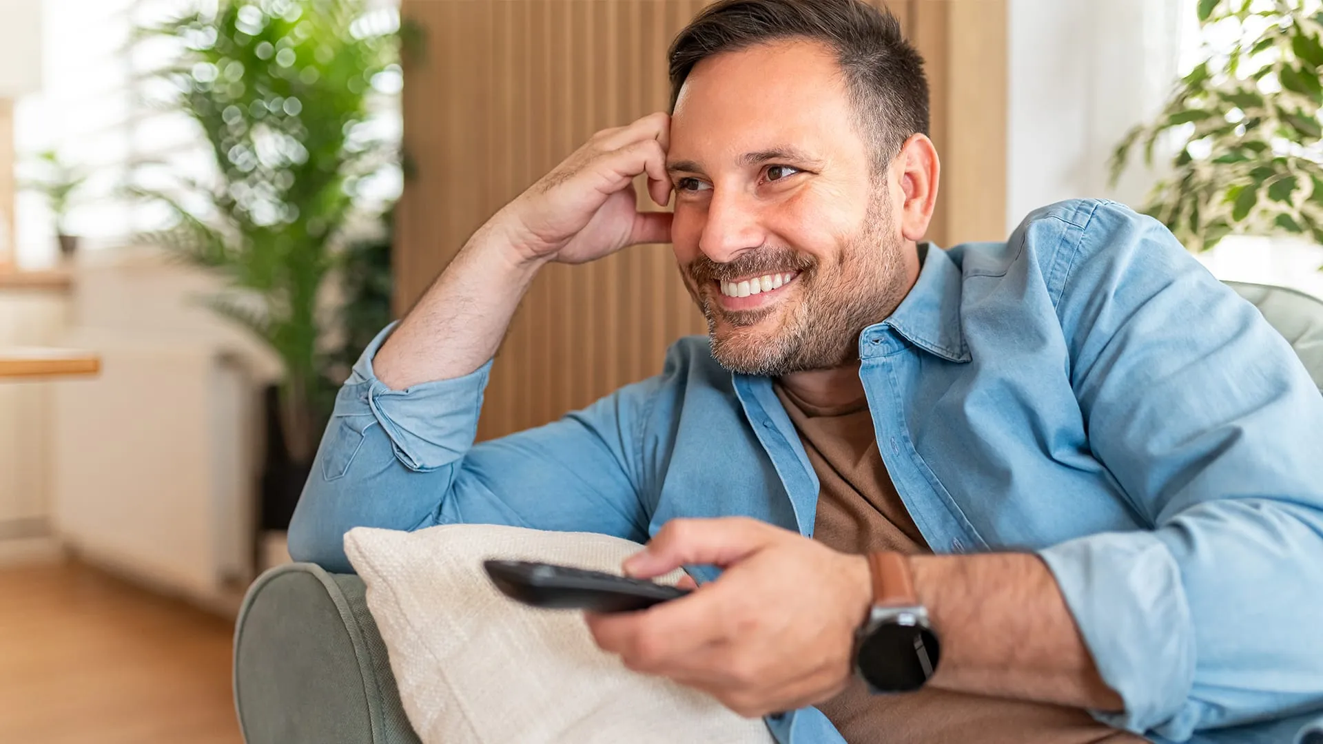 Man smiling holding TV remote