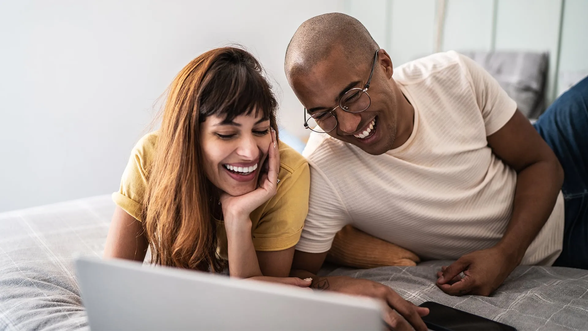 Man and woman smiling and using a laptop